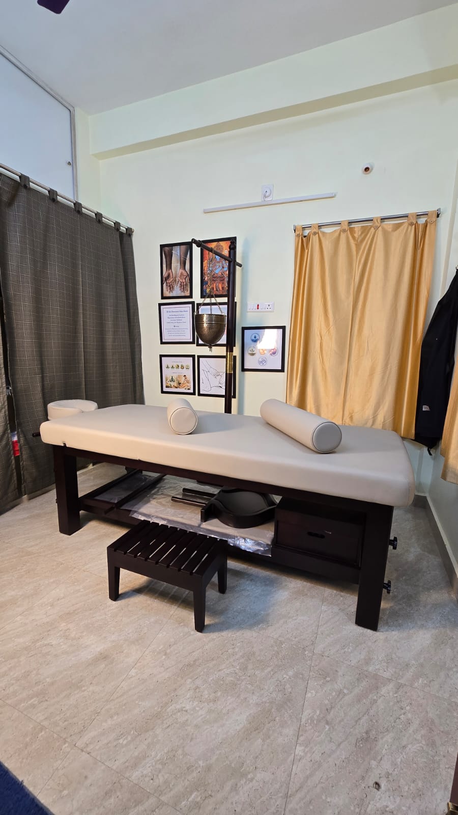 The AYU treatment room with Shirodhara stand and framed Ayurvedic art
